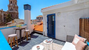 A rooftop terrace with a view of a historic building, a blue door, and a small table with stools. - Exclusive 2BD duplex in Malaga old town. San Agustin Terrace III (Malaga)