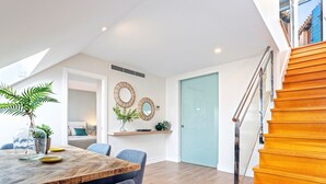 A modern dining area with a wooden table, chairs, and a view of the kitchen. - Exclusive 2BD duplex in Malaga old town. San Agustin Terrace III (Malaga)