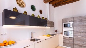 Una cocina moderna con gabinetes blancos, un lavamanos de acero inoxidable, un microondas y un horno.