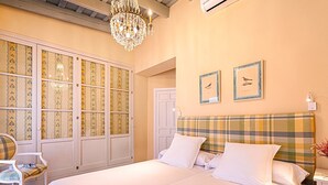 Un dormitorio con una cama grande, una araña, un armario con puertas estampadas y dos cuadros en la pared.