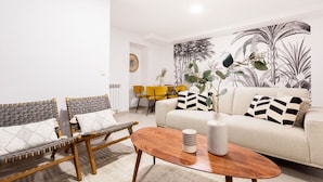 A modern living room with a sofa, two armchairs, a coffee table, and a dining area with yellow chairs.