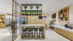 Una cocina moderna con una isla central, taburetes de bar y un separador de vidrio.