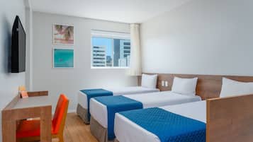Una habitació d'hotel amb dos llits individuals, una taula de treball amb una cadira, una televisió i una finestra que dona a una vista de la ciutat.