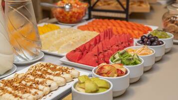 A buffet table with various fruits and a pitcher of iced tea.