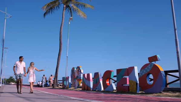A pathway with large colorful letters spelling 'MANCHESTER' and palm trees in the background.