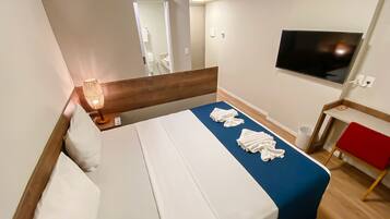 A hotel room with a bed, a TV, a desk, and a chair.