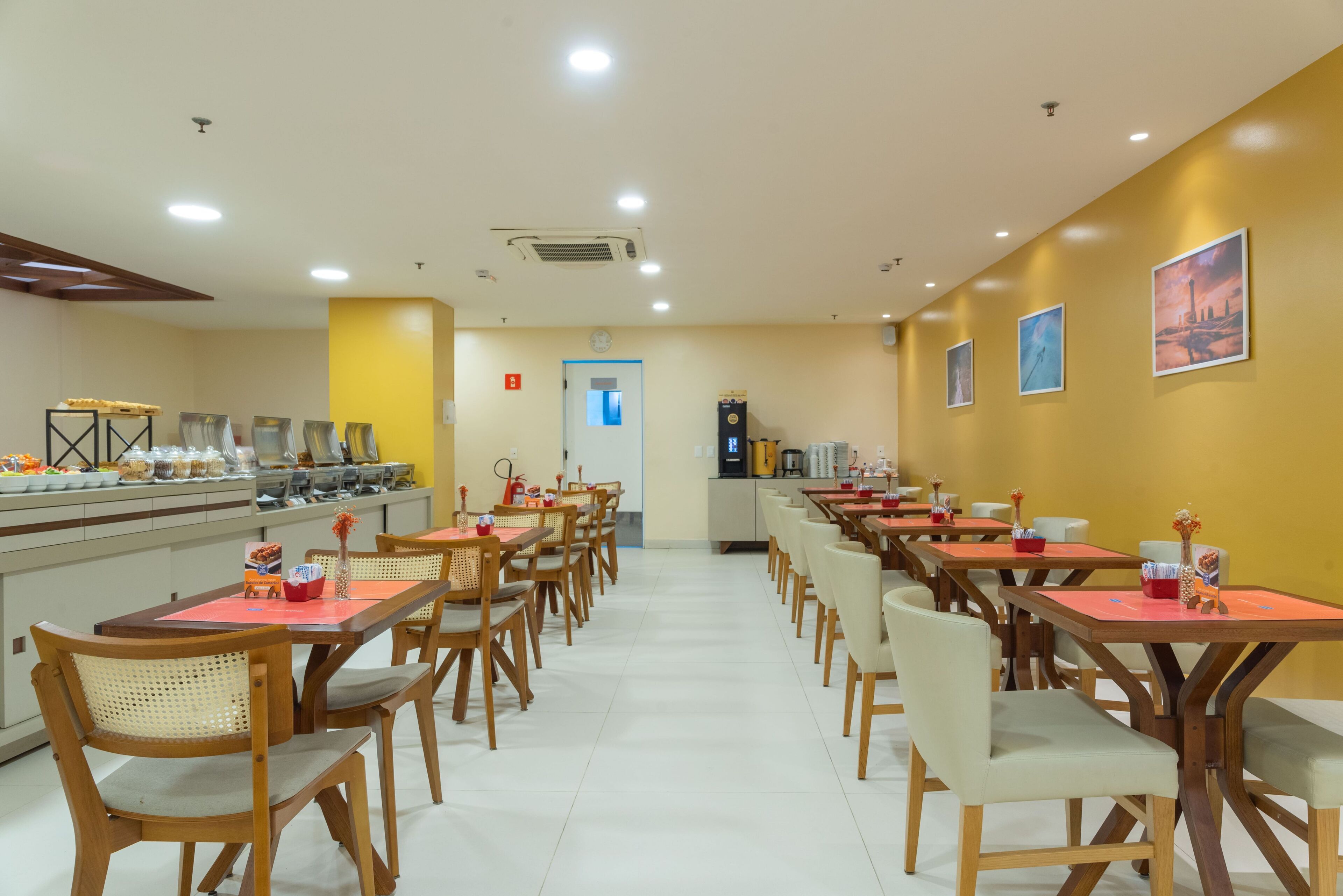 A spacious dining area with multiple tables and chairs, a buffet counter on the left, and a coffee machine on the right.