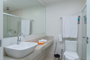 Un baño moderno con lavamanos, espejo y retrete blancos.