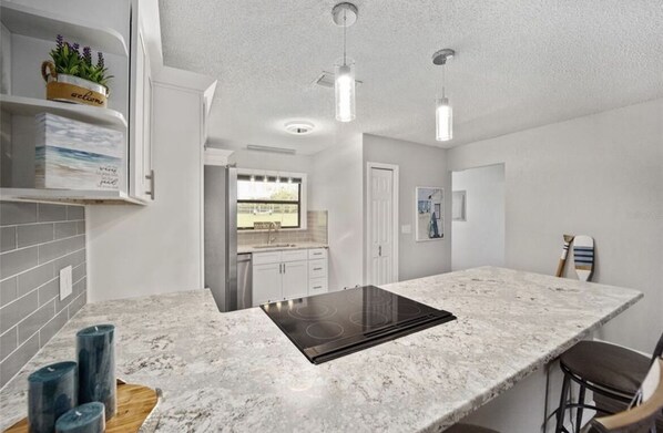 A modern kitchen with a central island, white cabinetry, and pendant lighting. - Lake Front Get Away - 10 minutes from The Villages (Summerfield)