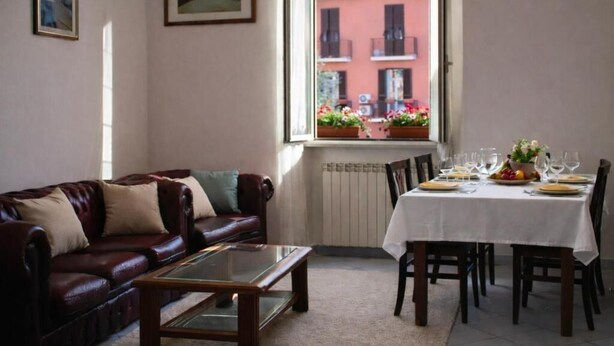 Un salon avec un canapé en cuir, une table basse en verre et un coin repas avec une table dressée pour quatre personnes.