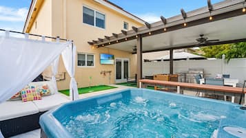 Un patio trasero con un jacuzzi, un porche techado y una mesa de billar.