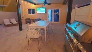 A patio with a white table and chairs, a ceiling fan, and a barbecue grill.