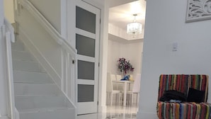A modern interior with a staircase, a dining area, and a colorful chair.