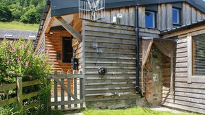A wooden cabin with a sloped roof, a wooden fence, and a stone pathway leading to the entrance.