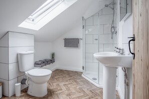 Ein modernes Badezimmer mit Oberlicht, Toilette, Dusche und Waschbecken.