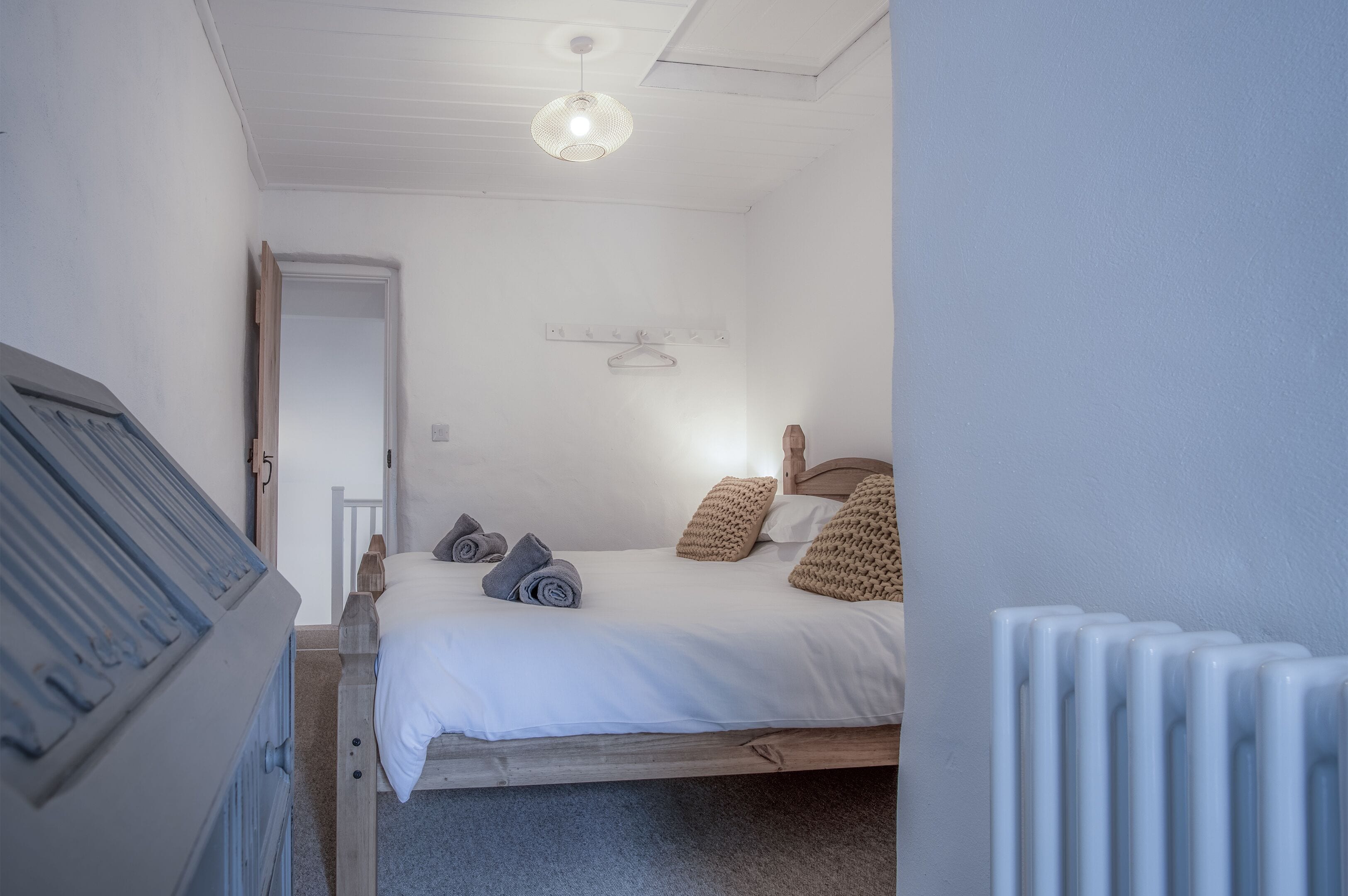 Ein Schlafzimmer mit einem Bett, einem Holz-Kopfteil, einem Heizkörper und einer Hängelampe.
