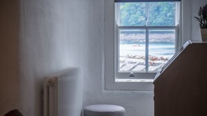 Ein Zimmer mit Blick auf den Strand, einem Heizkörper, einem kleinen Hocker und einem Holzschrank.
