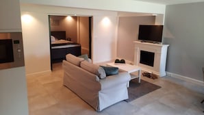 A modern living room with a sofa, a television, and a fireplace. - Souterrain "Edelweiss" (Noordwijk)