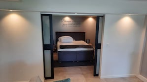 A bedroom with a bed, a nightstand, and a wall with a quote. - Souterrain "Edelweiss" (Noordwijk)