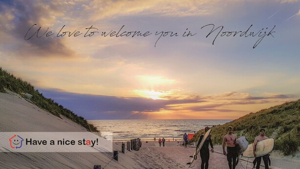 A beach scene with a sunset, people walking, and surfboards. - Souterrain "Edelweiss" (Noordwijk)