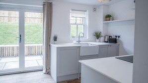 A modern kitchen with a large window, a sink, and a countertop. - Brook Cottage - 2 Bedroom Cottage - Dale (Haverfordwest)