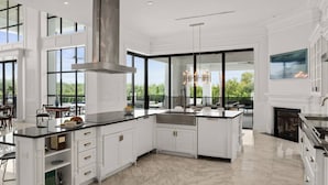 A spacious kitchen with white cabinetry, a large island, and a view of the outdoors.