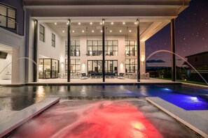 A modern house with a large pool, outdoor seating, and a staircase leading to the upper level. - 14BR Reunion Estate with Golf Course Views (Kissimmee)