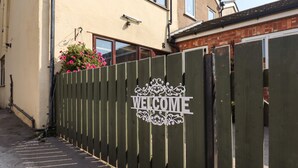 A residential building with a green fence and a 'WELCOME' sign.