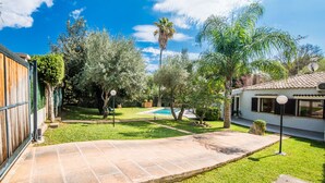 A backyard with a swimming pool, a wooden fence, and a house with a tiled roof. - House with pool garden Casa Pequeña in Mallorca (Crestatx)