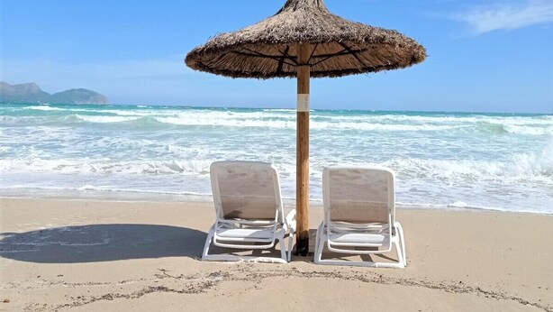 A beach with two white lounge chairs under a thatched umbrella, facing the ocean. - House with pool garden Casa Pequeña in Mallorca (Crestatx)