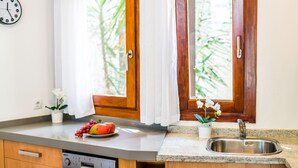 A kitchen with a dishwasher, a sink, and a window with curtains. - House with pool garden Casa Pequeña in Mallorca (Crestatx)