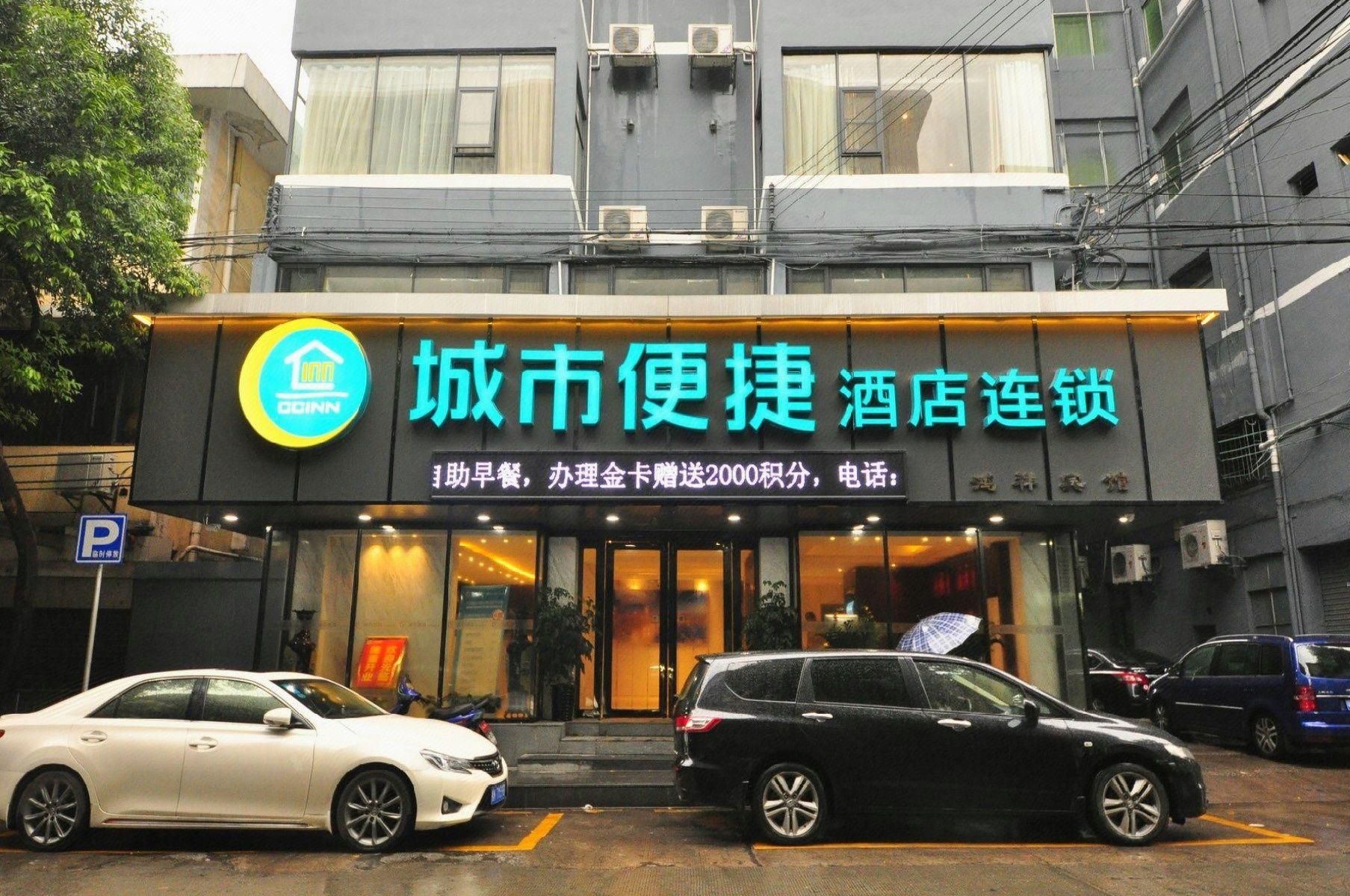 A building with a sign for a hotel chain. There are cars parked in front.