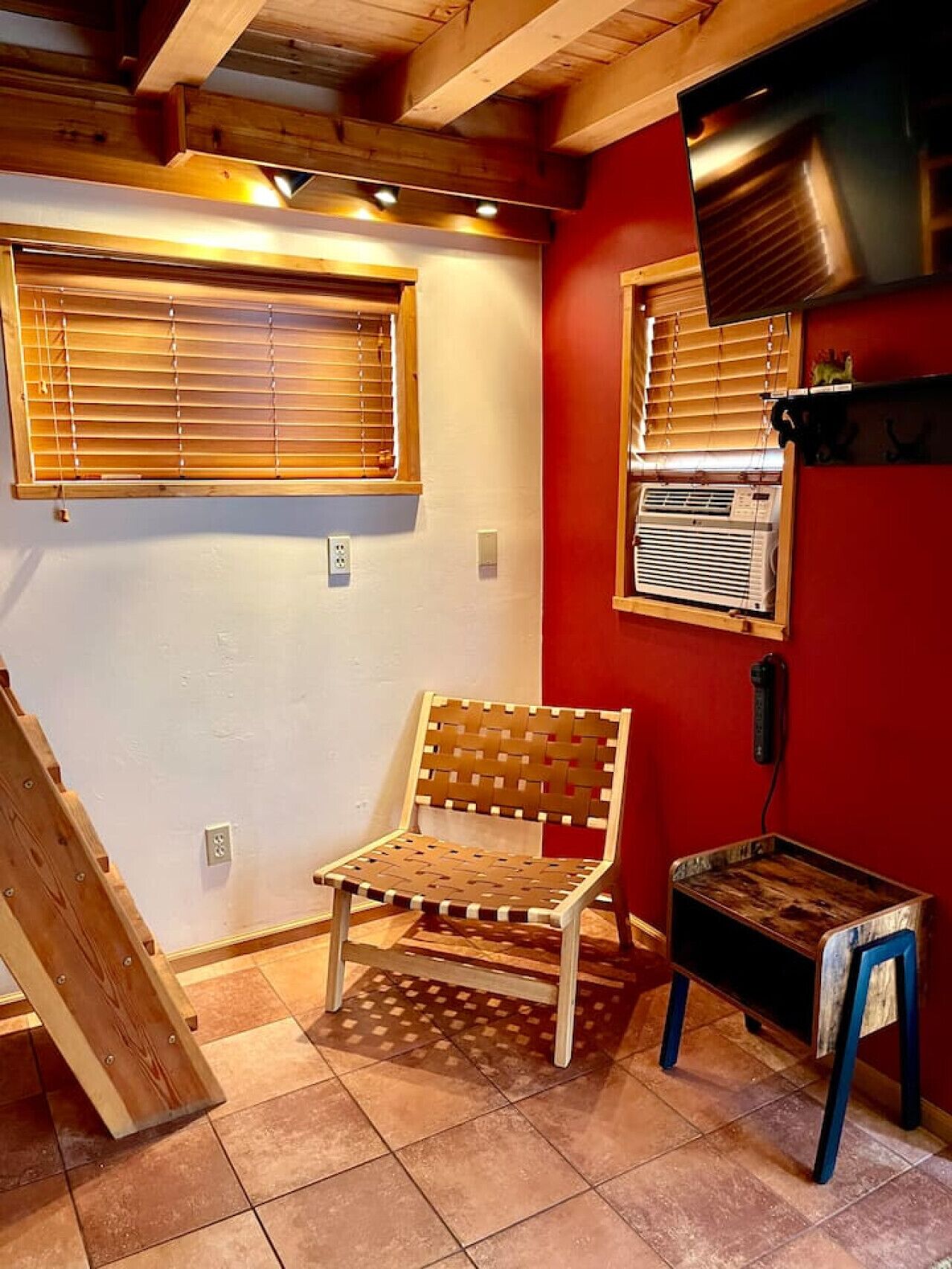 A room with a wooden bench, a small table, and a red wall.