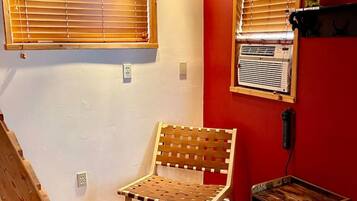 A room with a wooden bench, a small table, and a red wall.