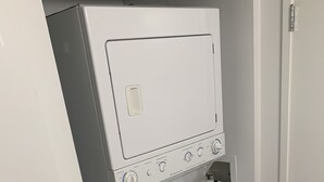 Ein kompaktes, weißes, an der Wand befestigtes Wasch- und Trockner-Kombigerät mit einer Bedienblende, die mehrere Drehregler und Knöpfe aufweist.