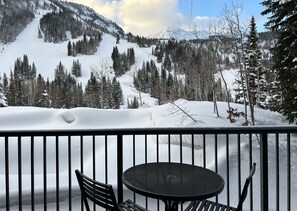 Relax on the balcony with a view of the snow-covered mountain landscape, featuring a round table and two chairs.