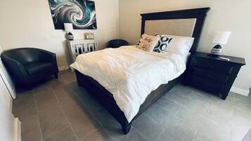A bedroom with a bed, a nightstand, a chair, a painting, and a Wi-Fi sign.