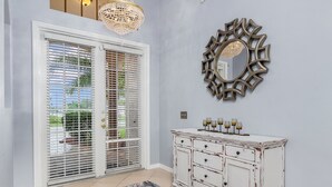 Una habitación con un armario blanco, un espejo decorativo y una araña.