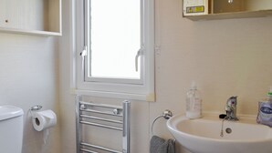 Un baño con inodoro, toallero, lavamanos y ventana.