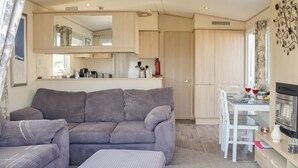Un espacio habitable compacto con sofá, reposapiés y una mesa de comedor con sillas.
