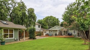 A residential backyard with a lawn, a patio area, and a small deck. - Cozy Multi-Property Bungalow in Central Austin - Cowboy pool (Austin)