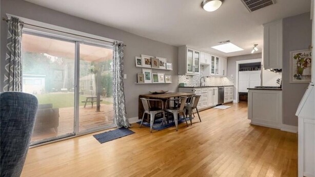 A spacious kitchen with white cabinets, a dining area with a table and chairs, and a large sliding glass door leading to a patio. - Cozy Multi-Property Bungalow in Central Austin - Cowboy pool (Austin)