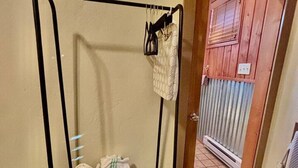 Une pièce avec un présentoir métallique où sont rangés des sacs et un panier contenant des serviettes pliées.