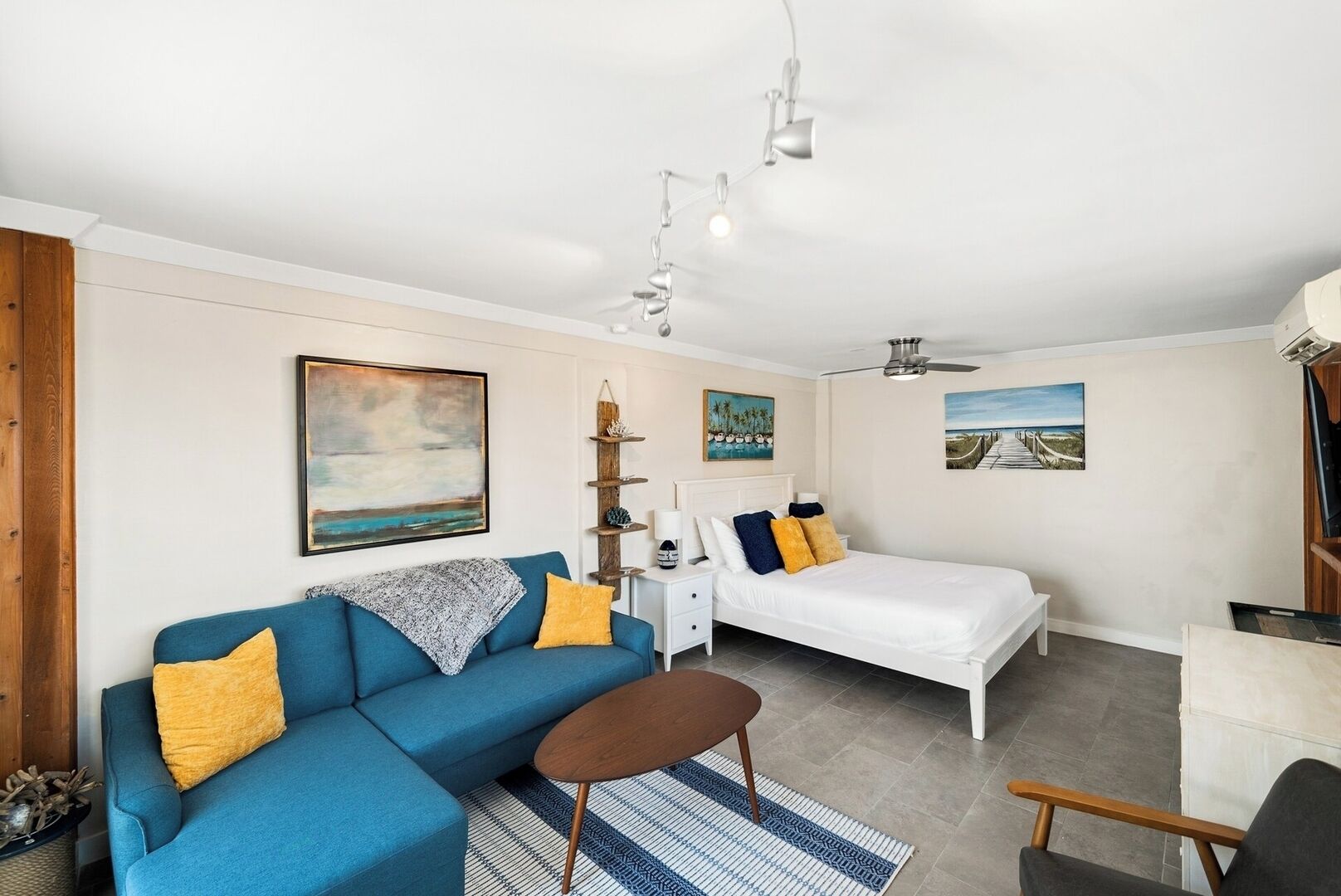 A modern bedroom with a blue sofa, a bed, a small table, and a TV.