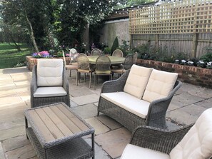 An outdoor patio with wicker furniture, a wooden table, and chairs. - Lyndhurst (Liverpool)
