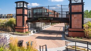 Een poort met een bord waarop 'Louisville' staat, boven een modern gebouw.