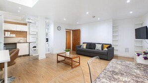 A modern living room with a grey sofa, a coffee table, and a dining area with a chair and table.