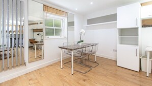 A modern kitchen with white cabinets, a wooden countertop, and a window with blinds.