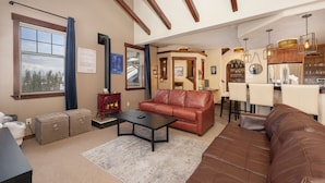 A living room with a fireplace, leather sofas, and a dining area with a kitchen in the background. - Hot Tub | Winter Getaway & Mountain Views (Fraser)