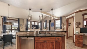 A spacious kitchen with a central island, stainless steel dishwasher, wooden cabinets, and pendant lighting. - Hot Tub | Winter Getaway & Mountain Views (Fraser)
